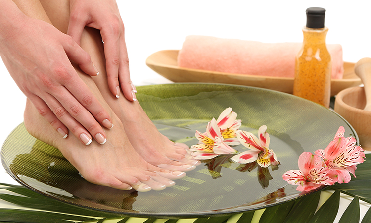 Female feet in spa bowl with water, isolated on white